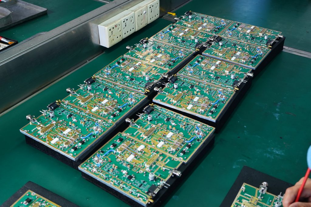 Engineer inspecting a conformal-coated RF PA PCBA under UV light before post-coating RF verification